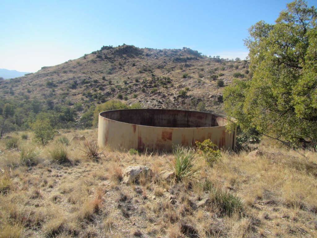 A photo of a large metal tank used for cattle, found deep in the Rincon wilderness. The tank is 7 feet tall and about 24 feet in diameter.